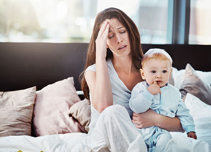 Stressed mother holding baby needing babysitting help