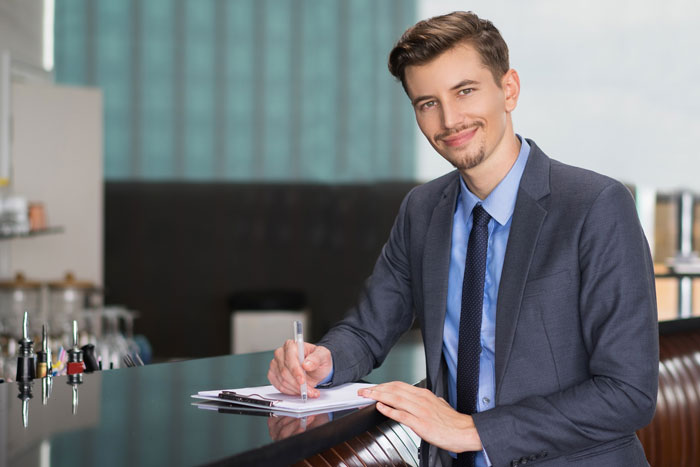Man smiling confidently in suit while writing at desk Man smiling confidently in suit while writing at desk