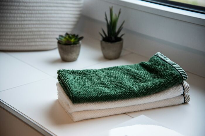 Stack of clean towels next to small potted plants by window