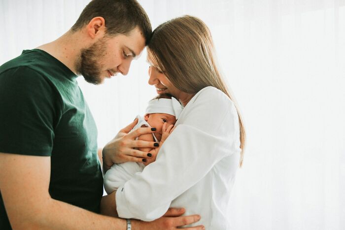 Young parents holding newborn baby relating to evil MILs family stories