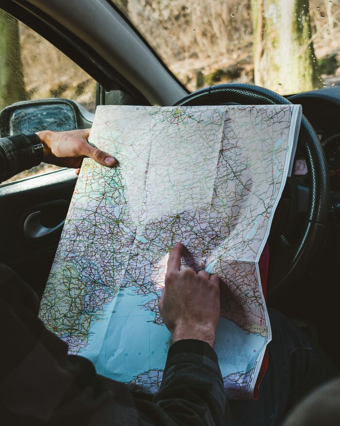 Person confused with map inside car illustrating brain on auto pilot mistake