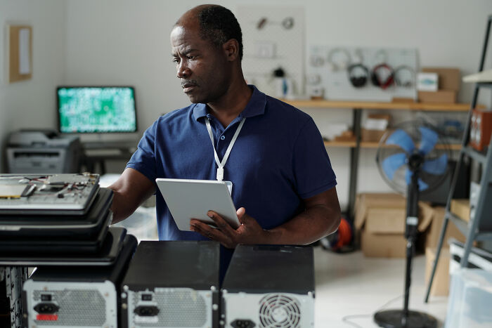 Man using tablet in workshop with computer parts showing quitting job for peace