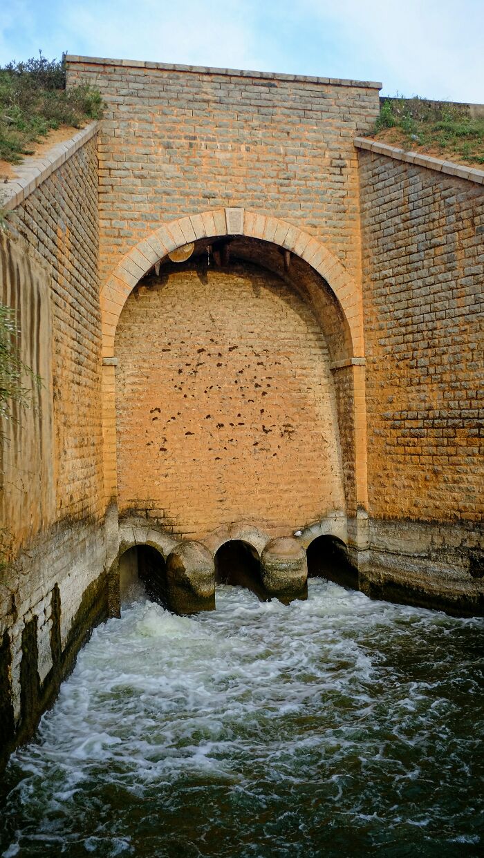 Water flowing from drainage tunnel in brick wall structure