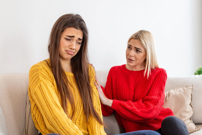 A tearful sister in yellow, being consoled by her blonde sibling in red, after the surprise room redecoration.