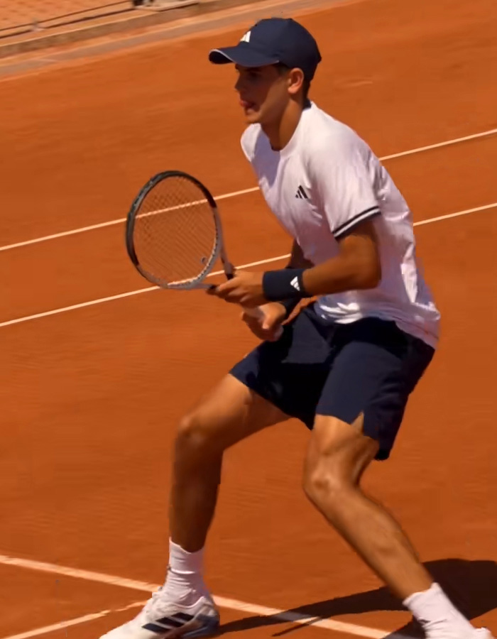 Young French Open tennis player preparing to return the ball on clay court