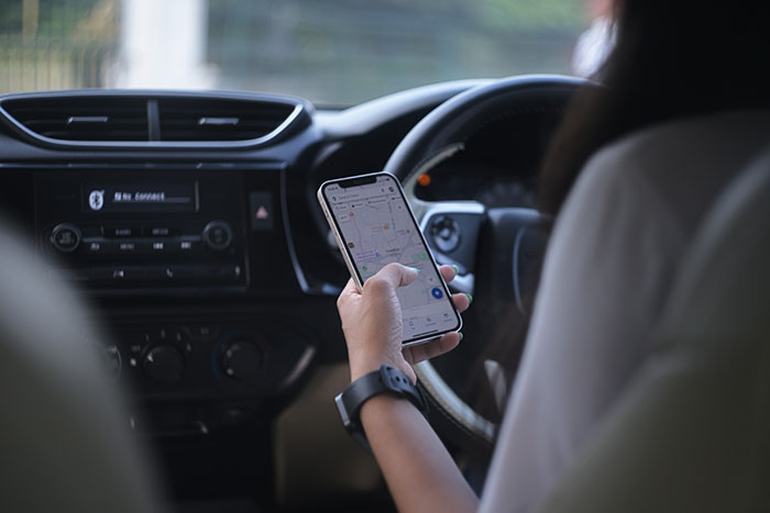 Driver using phone with right hand inside car, focusing on navigation map Driver using phone with right hand inside car, focusing on navigation map