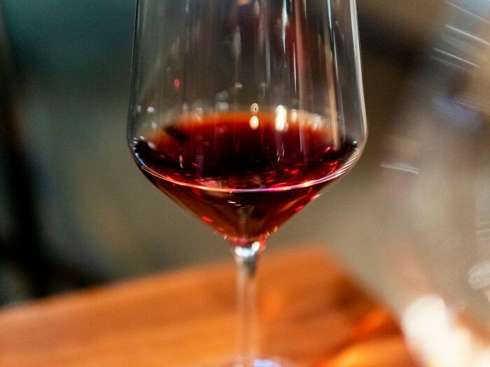 Wine glass filled with red wine on wooden surface at wedding reception