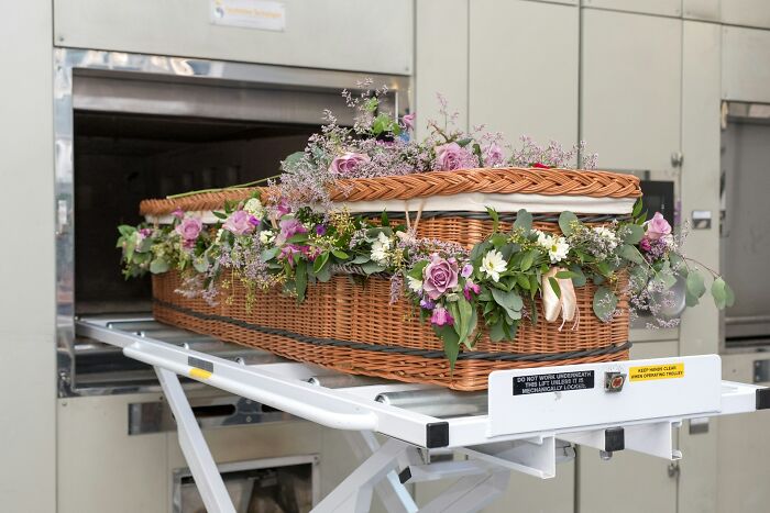 Wicker coffin decorated with purple flowers in cremation chamber
