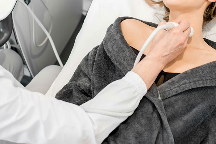 Doctor performing thyroid ultrasound examination on patient