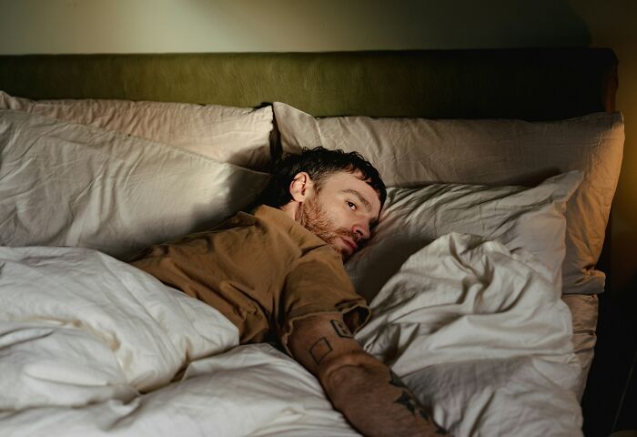 Tired man lying in bed looking fatigued and restless