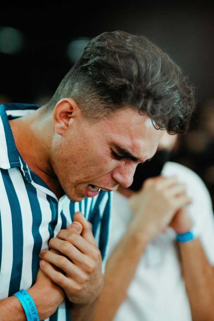 A man with curly hair, in a striped shirt, clenching his hands in an intense, emotional moment. Very creepy things experienced.