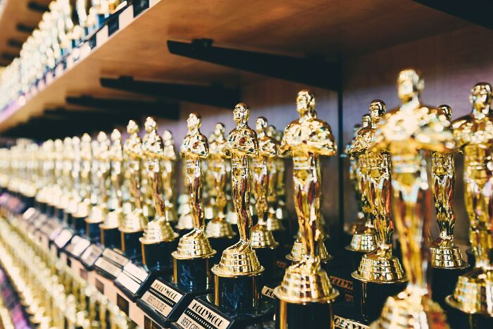 Rows of golden Hollywood Best Couple trophies, symbolizing the costs and experiences of celebrity relatives.