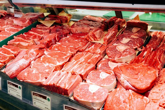 A butcher's display case filled with various cuts of fresh, red meat, an expensive habit that can save you money.