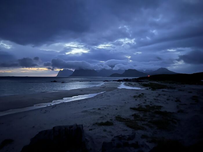 Rare moment of clouds enveloping mountains at dusk by the beach