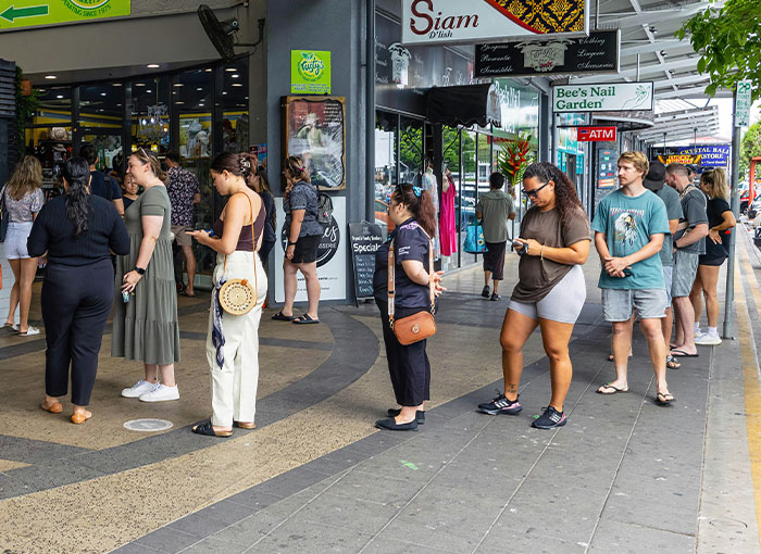 A queue of people waiting outside shops, illustrating unwritten rules like queueing etiquette, a British cultural norm.