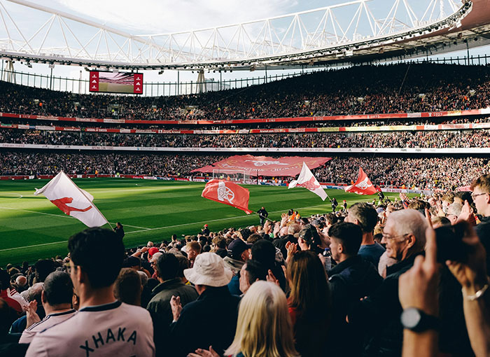A packed football stadium with fans waving flags, showcasing a Brit tradition. The vibrant crowd embodies unwritten rules of support.