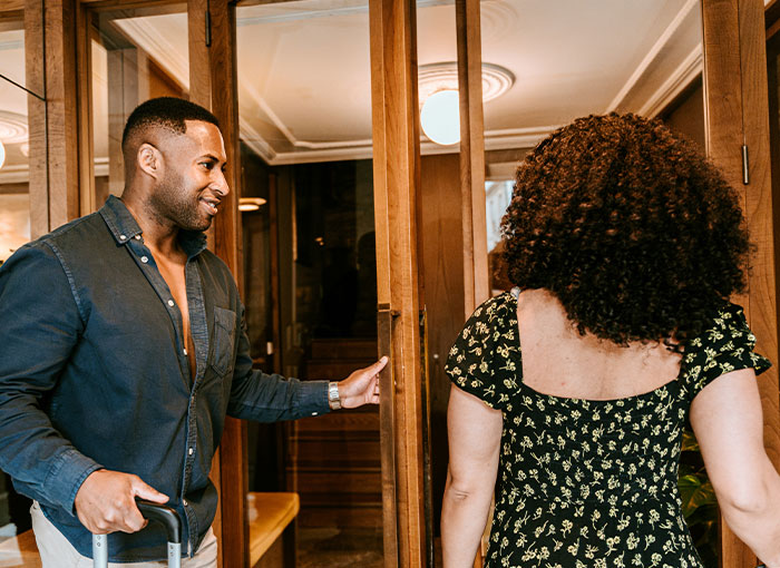 A man holding open a door for a woman, showing good manners. This highlights unwritten rules and British customs.