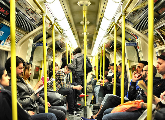 Passengers on a train, highlighting Brits and their unwritten rules, showing people sitting and standing inside a subway car.