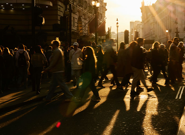 People crossing a sun-drenched street in a city, highlighting British unwritten rules and culture.