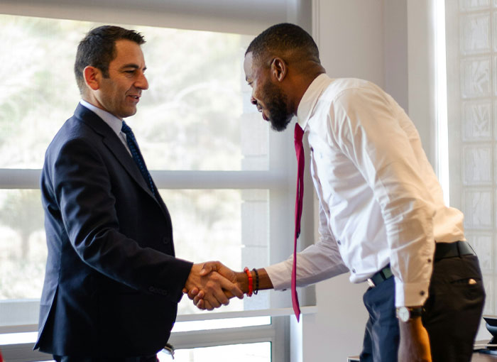 Two men shaking hands in a business setting, showcasing a common interaction. Relates to unwritten rules Brits might know.