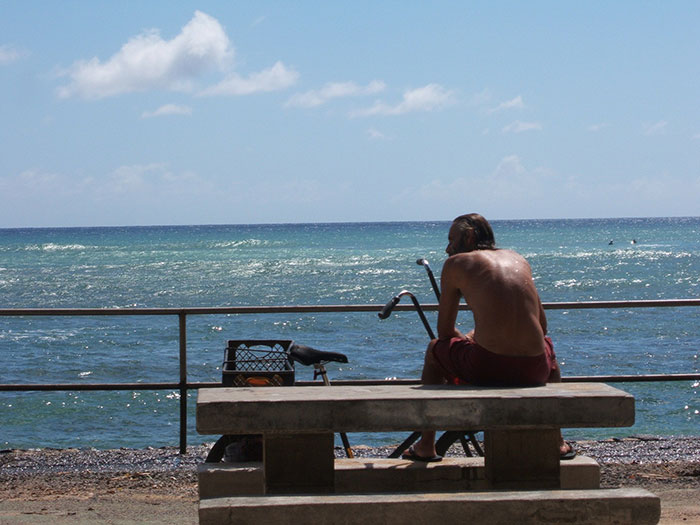 A person sitting on a bench by the ocean, enjoying the view of US states glorified in movies.