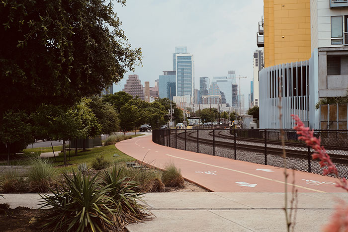 A modern city skyline with a bike path and train tracks, depicting US states in movies.