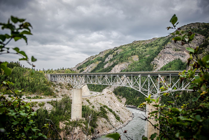 A majestic bridge over a river, surrounded by mountains and trees, showcasing US states.