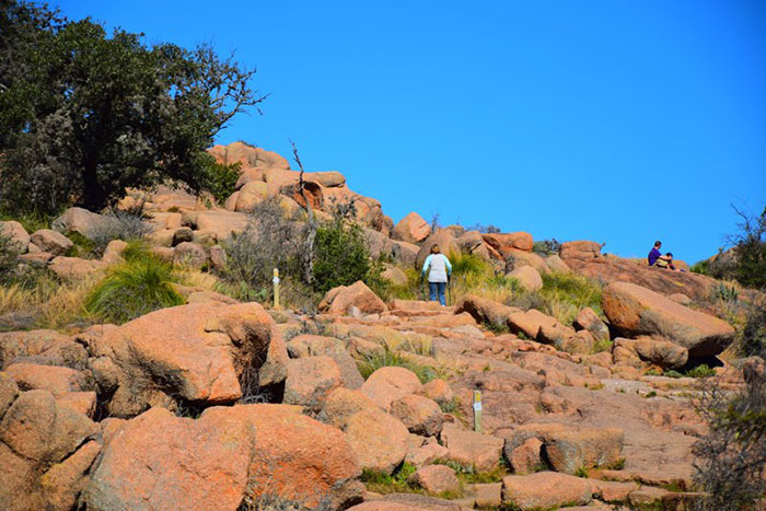 Hikers ascending a rocky, arid mountain landscape, depicting US states glorified in movies.