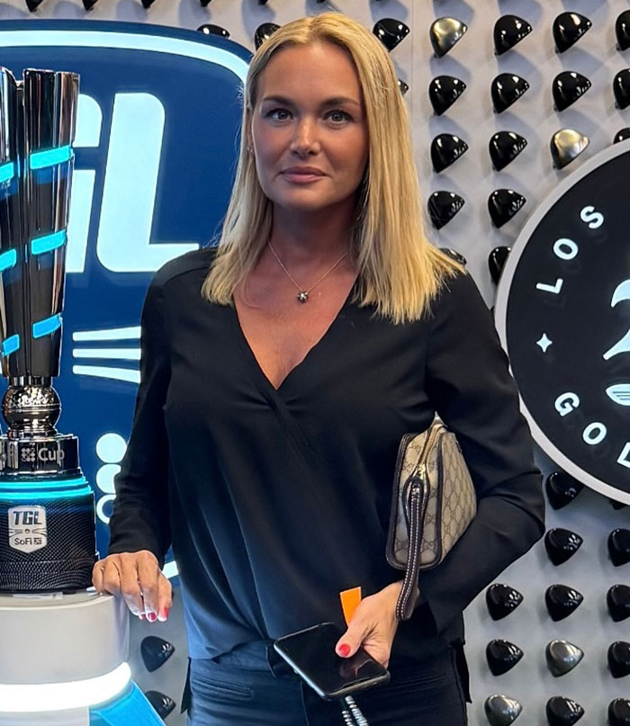 Vanessa Trump in a black top, holding a phone and bag, with a trophy, after revealing her harrowing diagnosis.