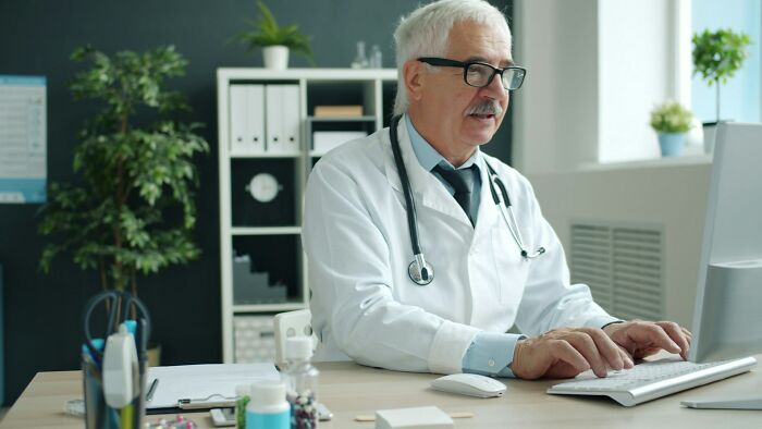 Doctor with stethoscope working on computer in medical office