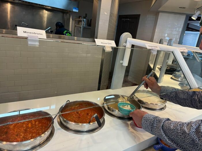 Health inspector showing soups including minestrone and chili at food counter