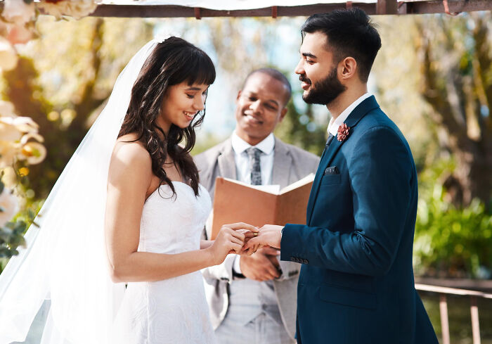 Bride putting ring on groom’s finger during wedding vows