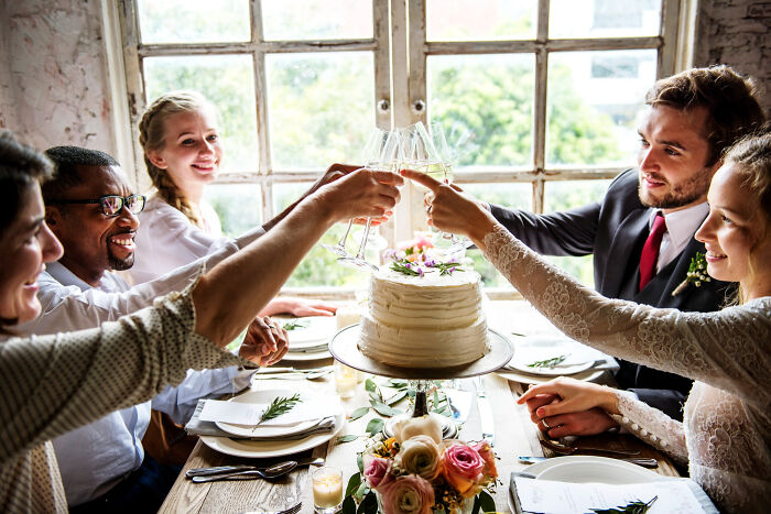 Wedding guests toasting with champagne around cake at wedding reception
