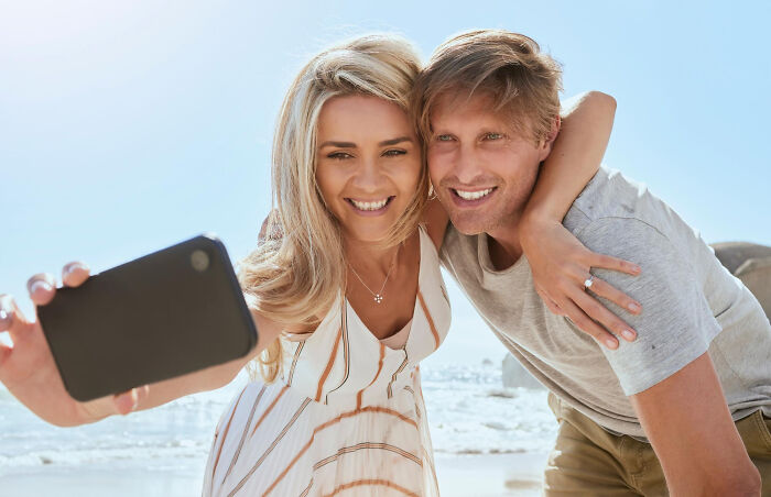 Happy couple taking selfie together on a sunny beach