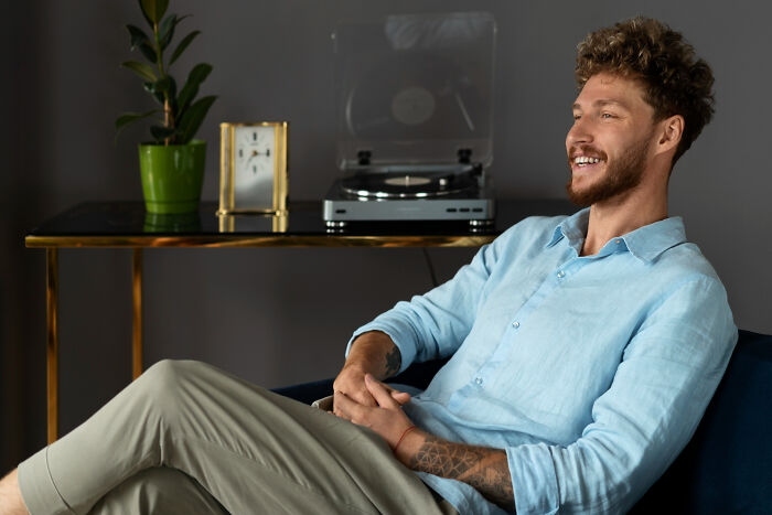 Man smiling and relaxing indoors with record player in background