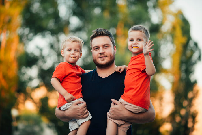 Father holding two young boys smiling outdoors family wedding moment