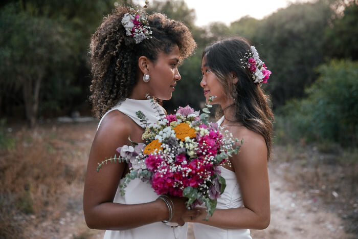 Two brides holding bouquet facing each other at wild weddings