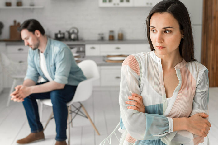 Woman looking upset with arms crossed while man sits in background