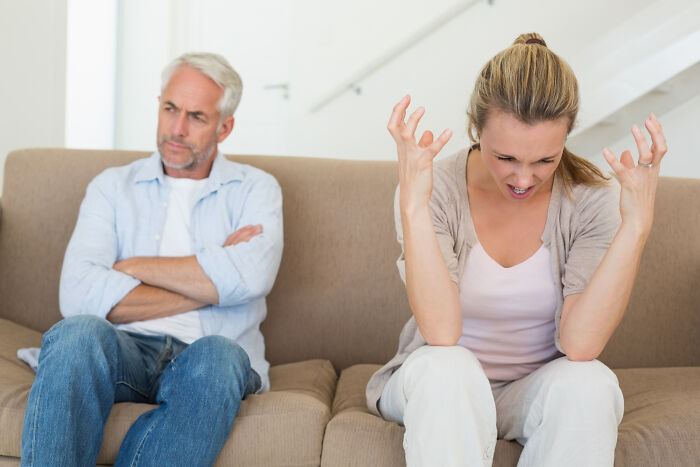 Frustrated couple arguing on couch showing wedding relationship strain