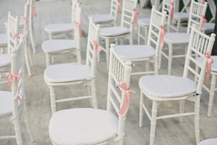 White chairs with pink ribbons arranged for a wedding ceremony