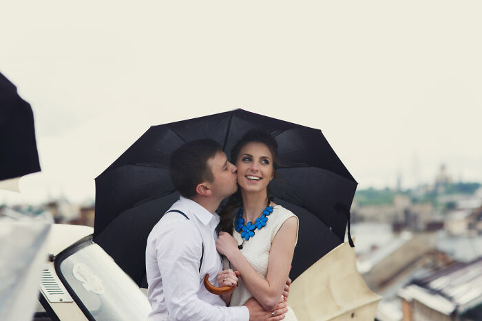 Couple under umbrella sharing a kiss at a wild wedding outdoors