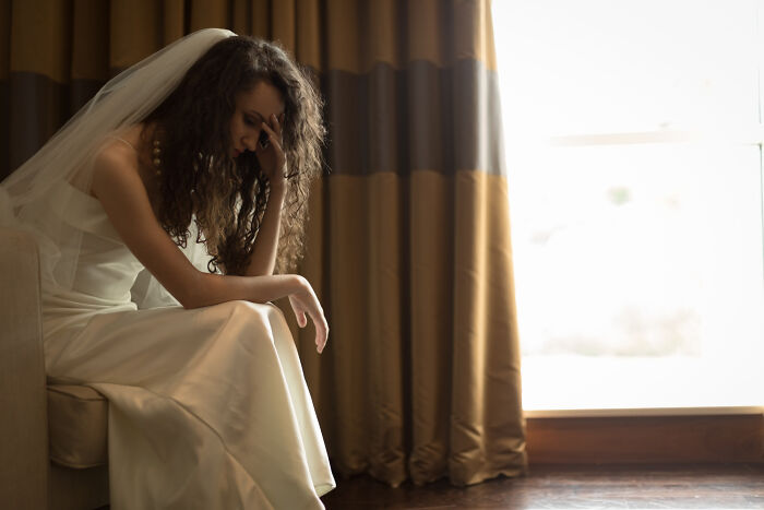 Bride in wedding dress sitting alone distressed before ceremony