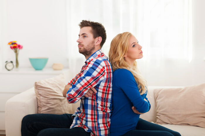 Couple sitting back to back looking upset showing a troubled wedding relationship