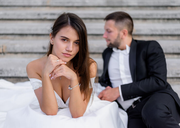 Bride and groom sitting on stairs looking distant