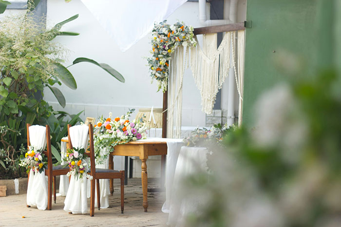 An outdoor wedding setup with two chairs and a table adorned with vibrant floral arrangements, hinting at marriage moments.