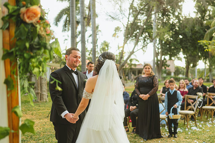 A couple holding hands during an outdoor wedding ceremony, with guests watching. Many wedding moments happen like this.
