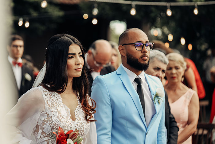 A serious-looking bride in a lace dress and groom in a light blue suit attend their wedding. Many wedding moments happen.
