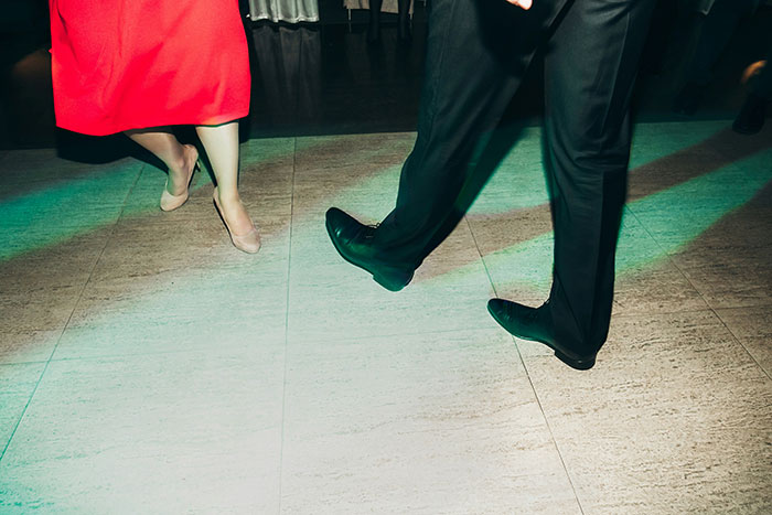 Feet of two wedding guests dancing on a tiled floor with green light, capturing a classic wedding moment.