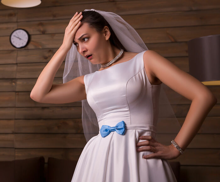 Stressed bride in wedding dress holding her head indoors