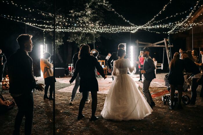 Guests dancing under string lights at outdoor wedding reception